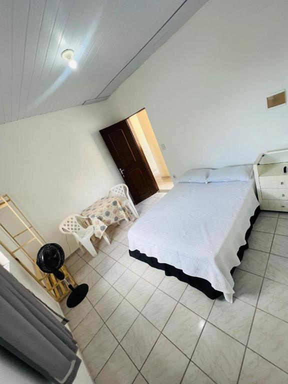 a white bedroom with a bed and a chair at Suite Aconchegante com ampla Area externa - Green in São Luís