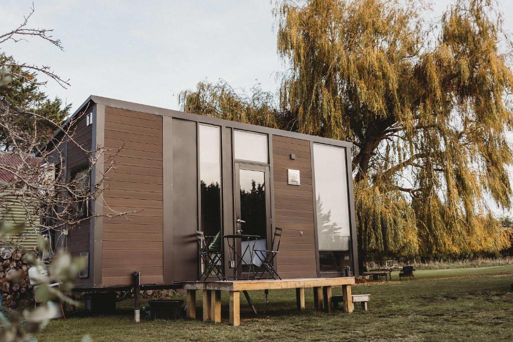 a tiny house with glass windows and a table at Matariki Akura by Tiny Away in Masterton