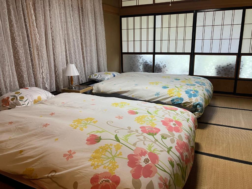 two twin beds in a room with windows at 一棟貸ひなたぼっこくらなみ in Nagano