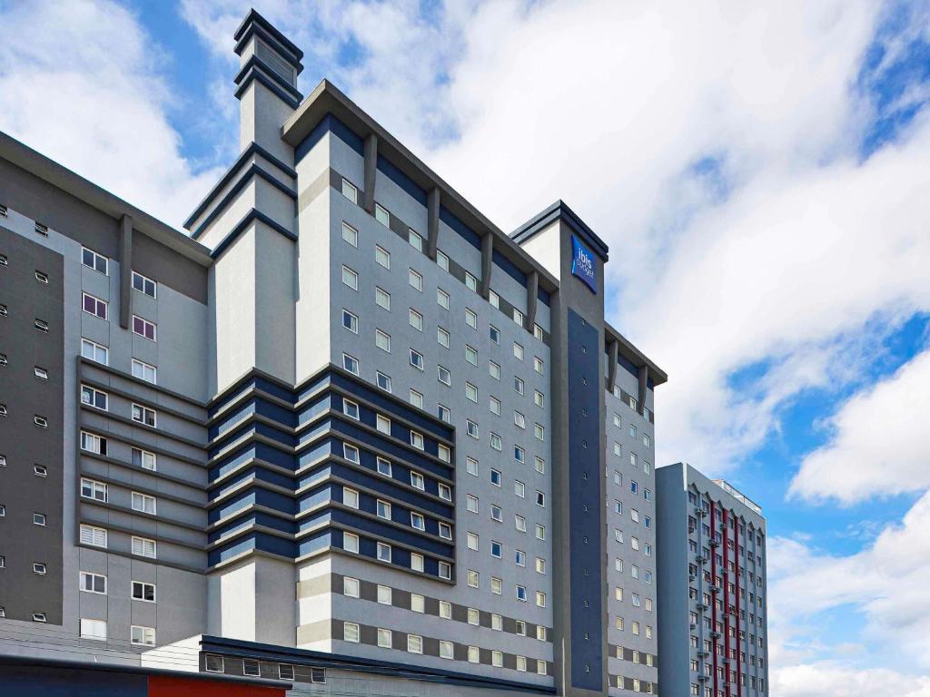 a tall building with a blue sky in the background at ibis budget Curitiba Centro in Curitiba
