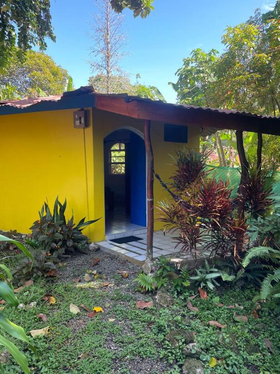 a small yellow house with a door in a yard at Cozy cabin by the sea in Cahuita