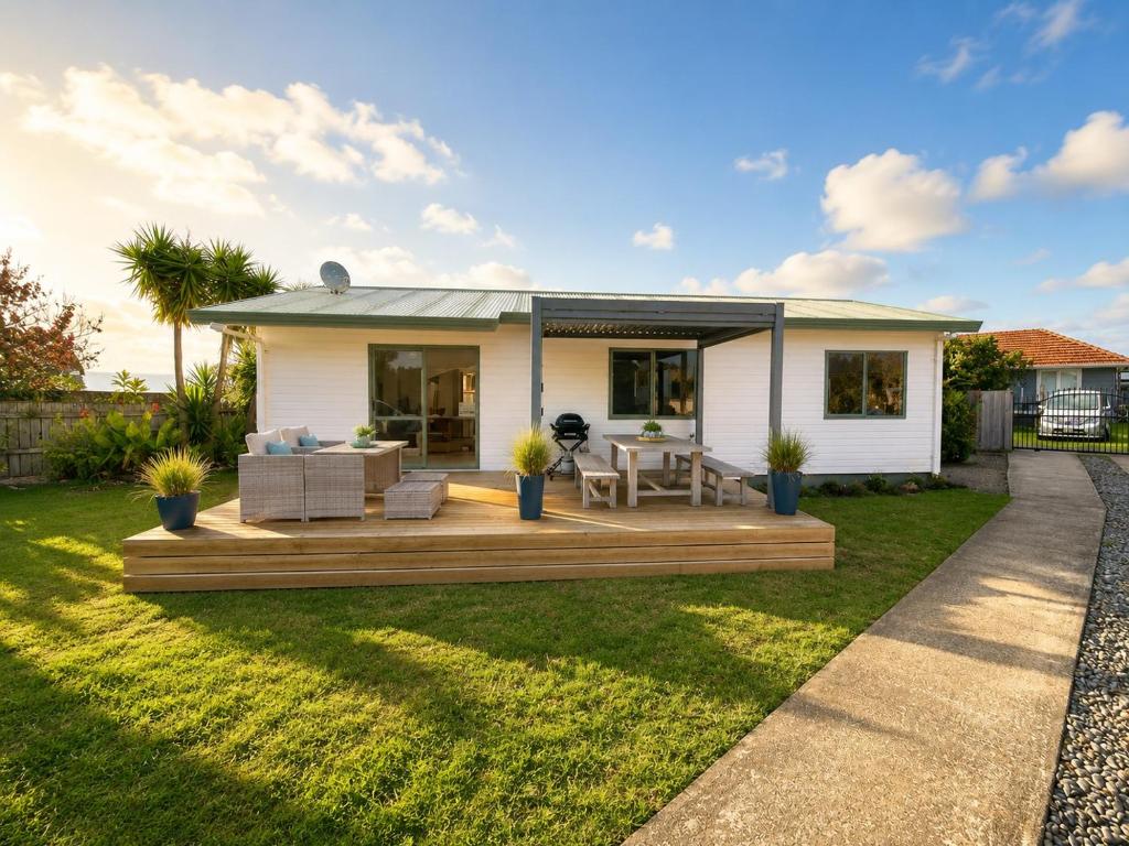 a small white house with a deck at Hosts on the Coast Make Memories on Cook in Whitianga