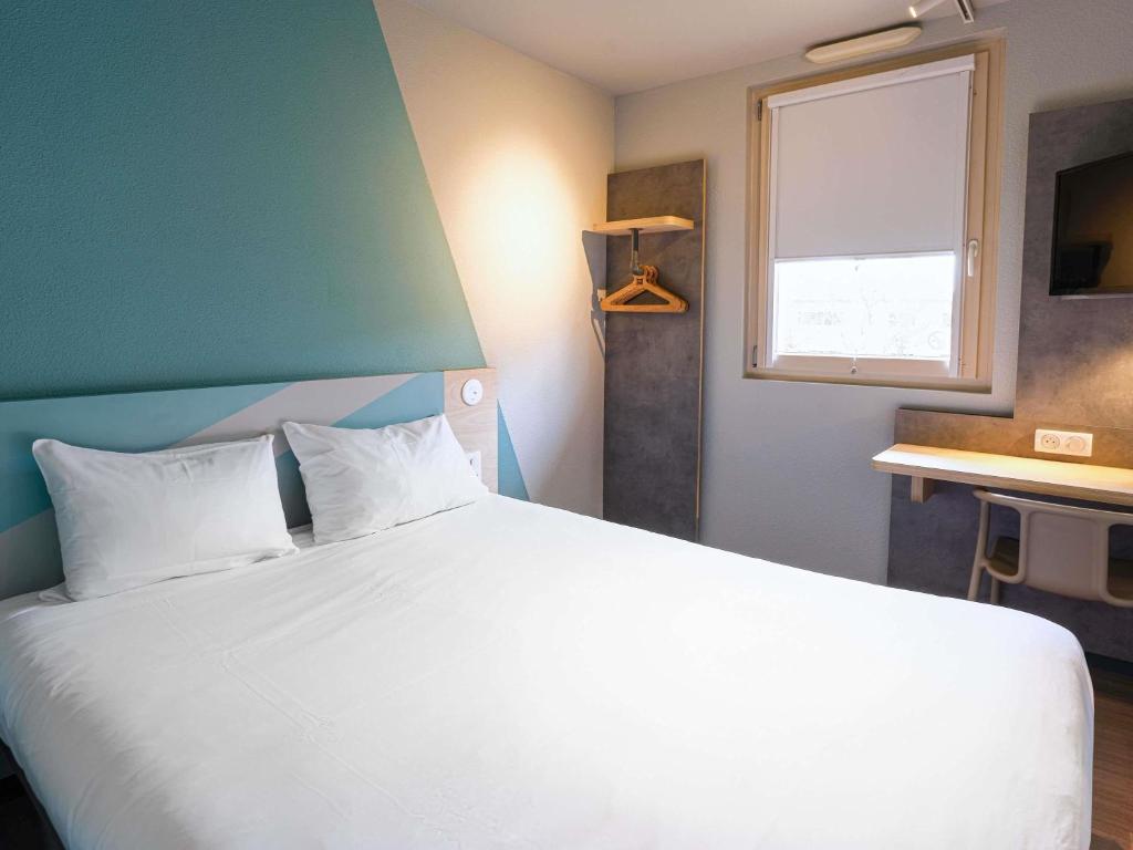 a bedroom with a large white bed with a window at ibis budget Bourg en Bresse in Bourg-en-Bresse