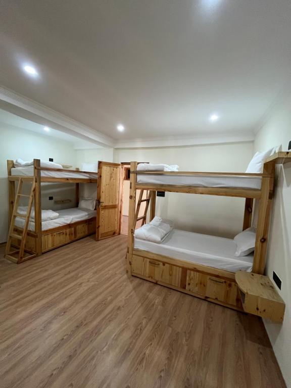 a room with three bunk beds and a wooden floor at Snow Den hostel in Leh