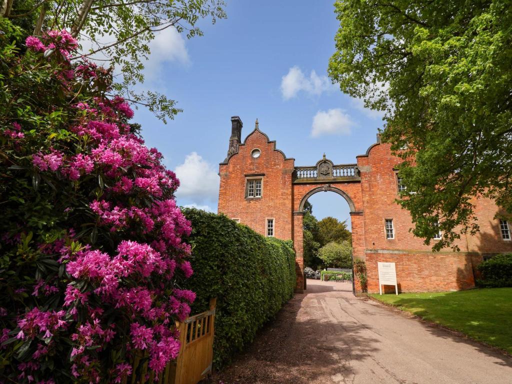 an entrance to a brick building with pink flowers at South Tower Cottage in Macclesfield