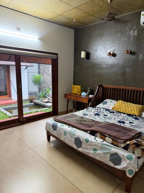 a bedroom with a bed and a large window at Bodhi nila private villa in Irimbranallūr