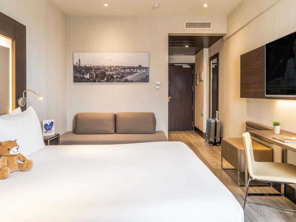 a hotel room with a large bed and a couch at Novotel Madrid Center in Madrid