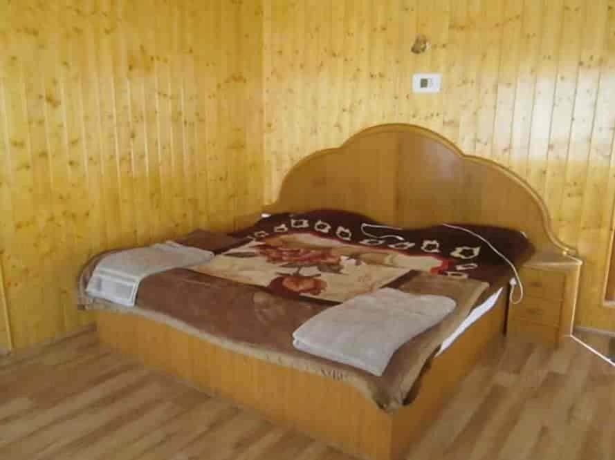 a bedroom with a bed in a wooden room at Pine inn in Pahalgām