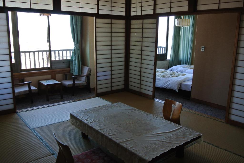 een kamer met een bed en een tafel en stoelen bij Kinpokan in Toba