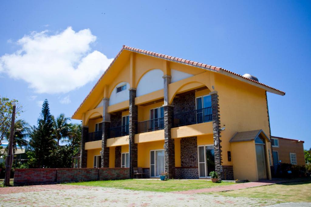 a large yellow building with a porch at Millennium Inn II in Kenting