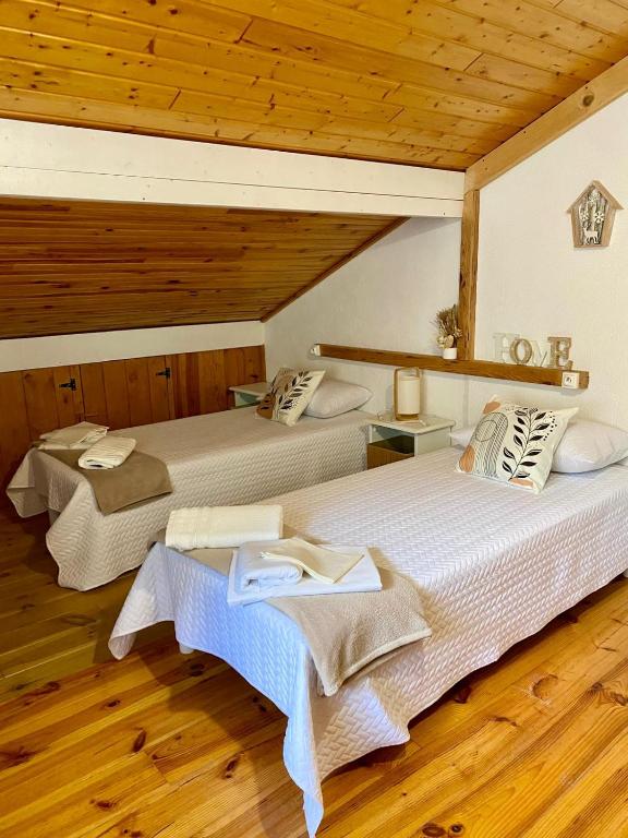 two beds in a room with wooden floors at STUDIO L'ISERAN, et GARAGE pour motos et vélos, gare à 800m in Fourneaux