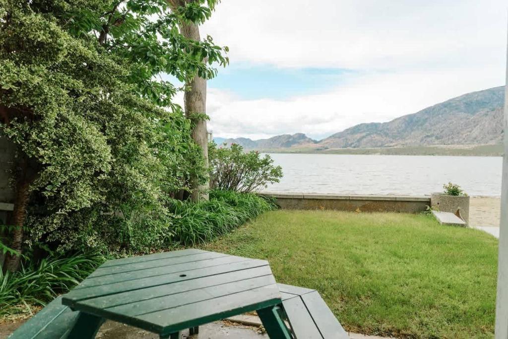 a green picnic bench sitting next to a lake at Studio Suite 8 Green Gables Resort in Osoyoos