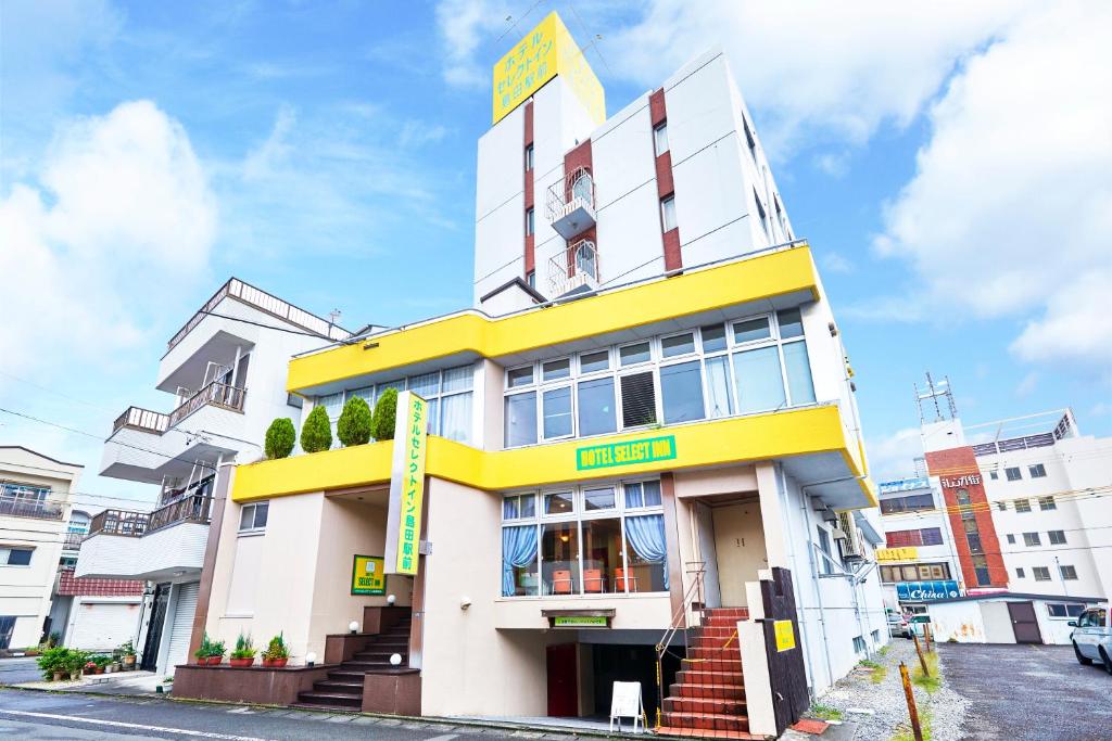 a yellow and white building on a city street at Select Inn Shimada Ekimae in Shimada