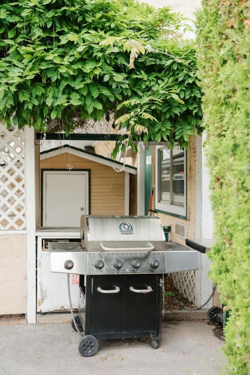 a barbecue grill in front of a house with a bush at Studio Suite 7 at Green Gables Resort in Osoyoos