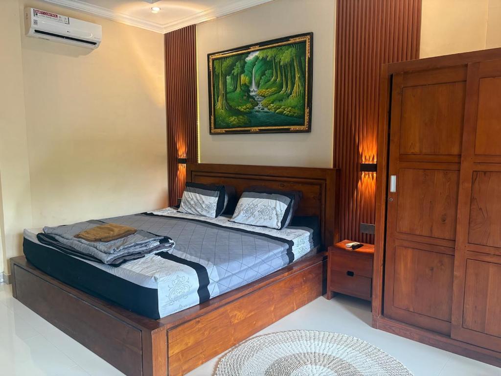 a bedroom with a bed and a painting on the wall at Dede House 1 Private Pool in Ubud