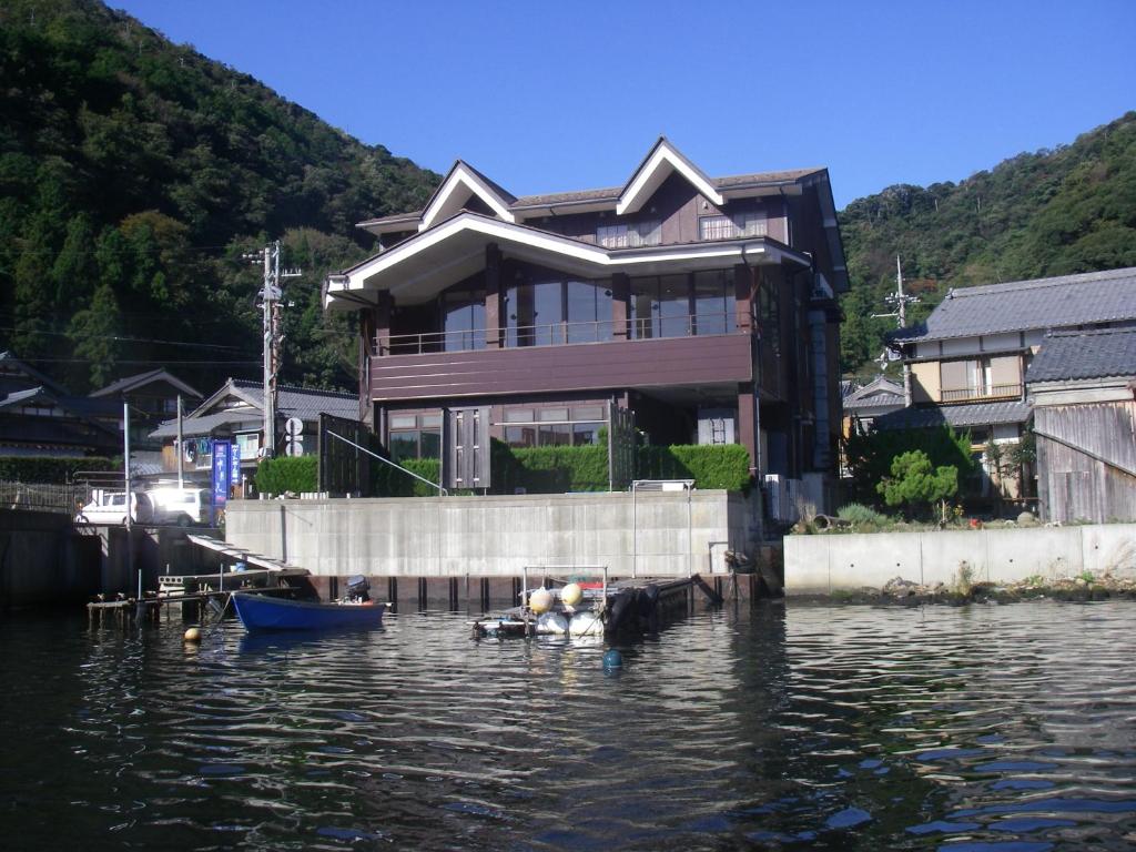 ein Haus auf dem Wasser mit einem Boot im Wasser in der Unterkunft 湖上館パムコ in Wakasa