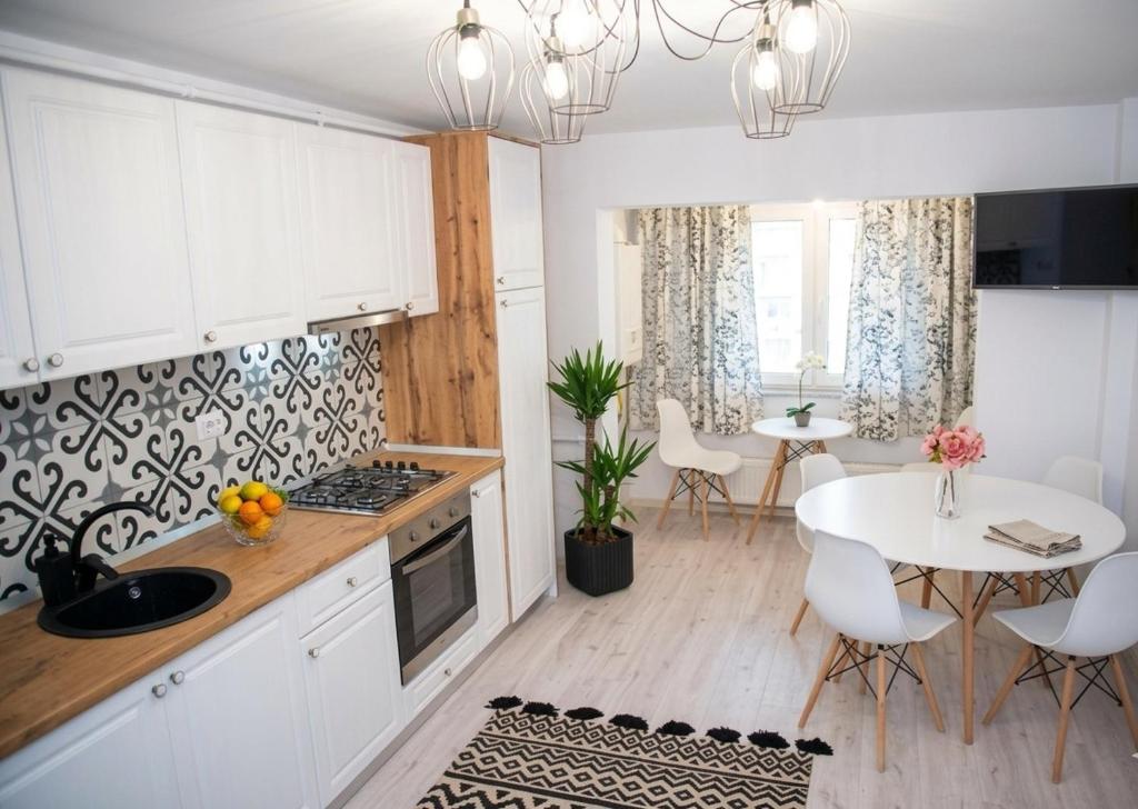 a kitchen with white cabinets and a white table with chairs at Apartament Daria in Târgu Ocna