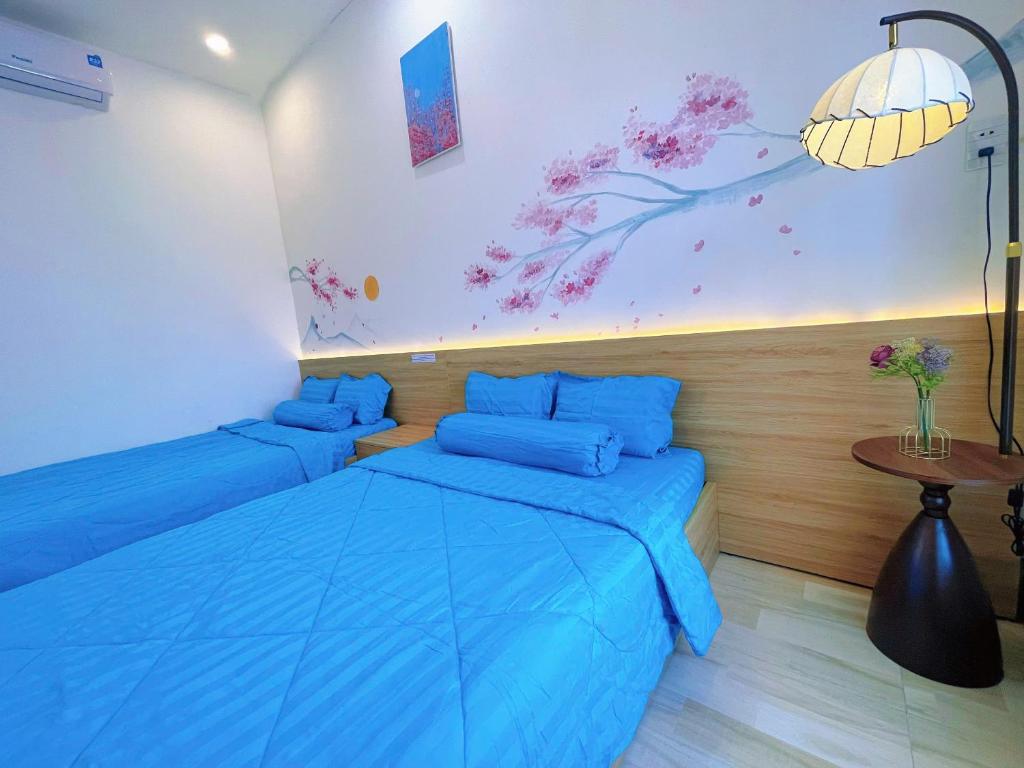 a bedroom with two beds with blue sheets and a table at Mie's Homestay in Danang