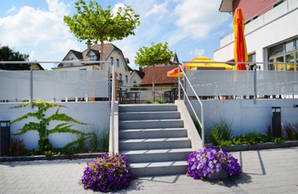 un conjunto de escaleras con flores púrpuras delante de una valla en Hotel Garni Bären Bazenheid, en Bazenheid