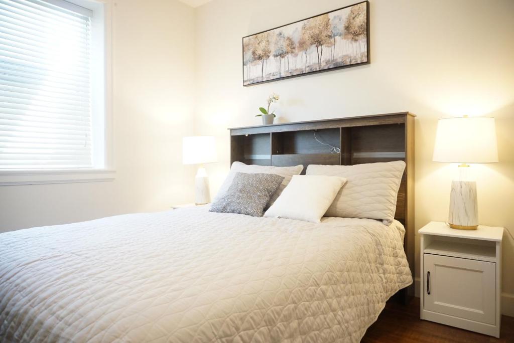 a bedroom with a large bed with a white bedspread at the blossom stay in Burnaby