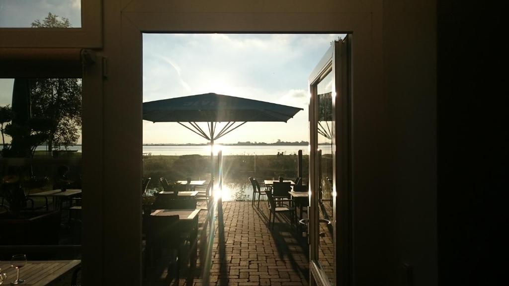 eine offene Tür zu einer Terrasse mit einem Sonnenschirm in der Unterkunft Landhaus Großes Meer in Südbrookmerland