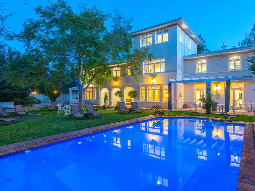 a house with a swimming pool in front of a house at Summerwood Guest House in Stellenbosch