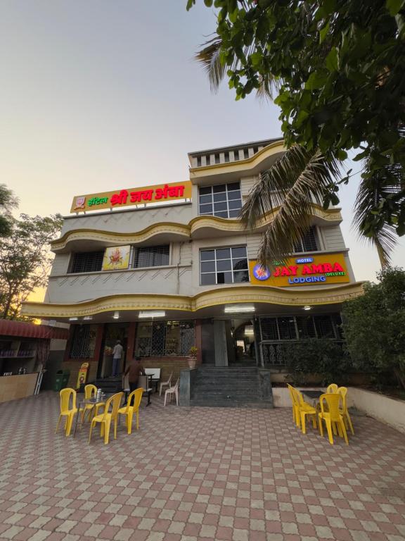 a building with yellow chairs and tables in front of it at Hotel Shree Jay Amba Deluxe in Jaisingpur