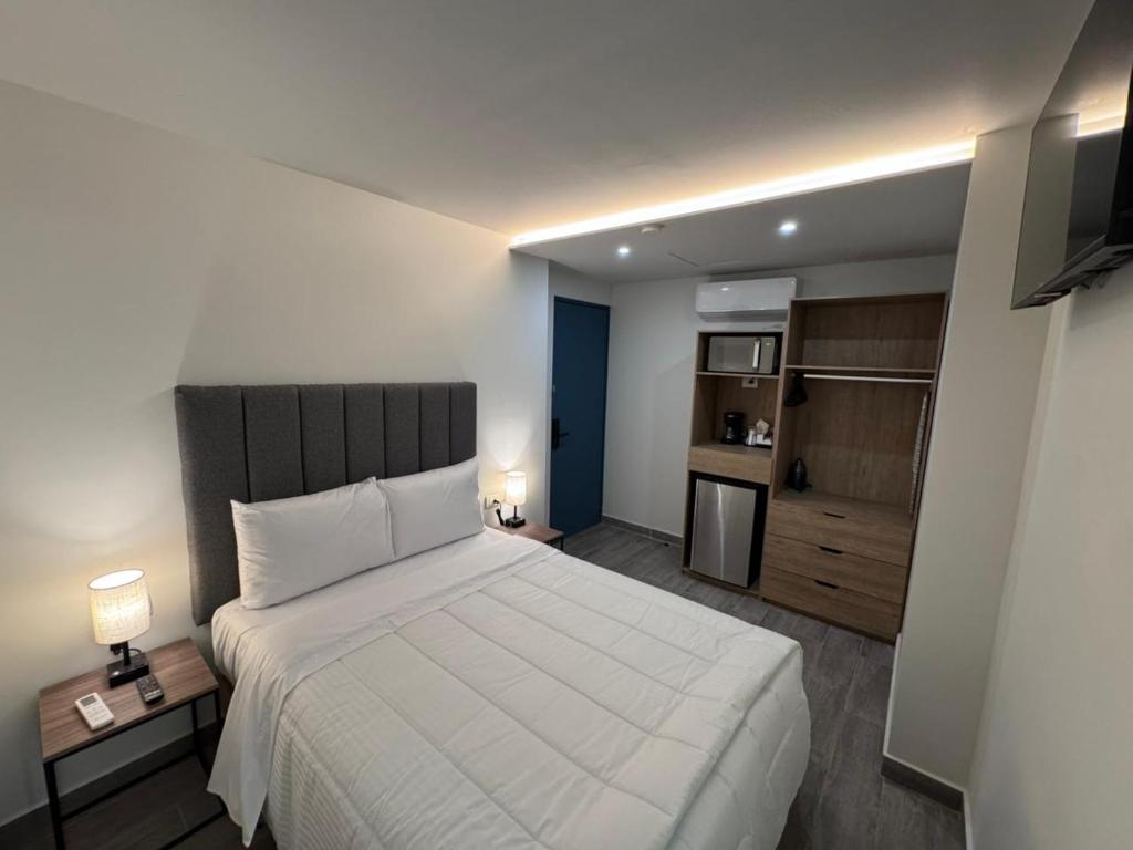 a bedroom with a large white bed and a kitchen at San Jeronimo Suites in Monterrey