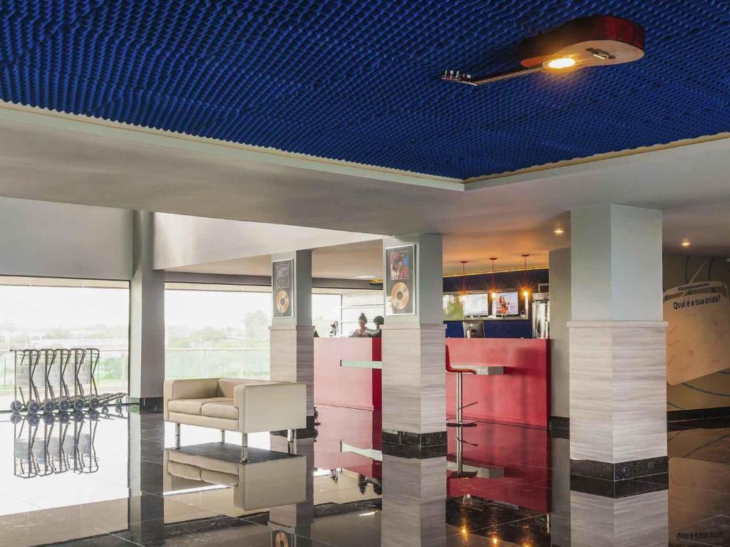 a room with a blue ceiling with chairs and tables at ibis Styles Sao Mateus in São Mateus
