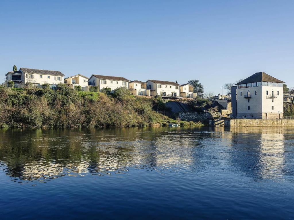 a view of a river with houses and buildings at Hôtel Mercure Villeneuve sur Lot Moulin de Madame in Villeneuve-sur-Lot