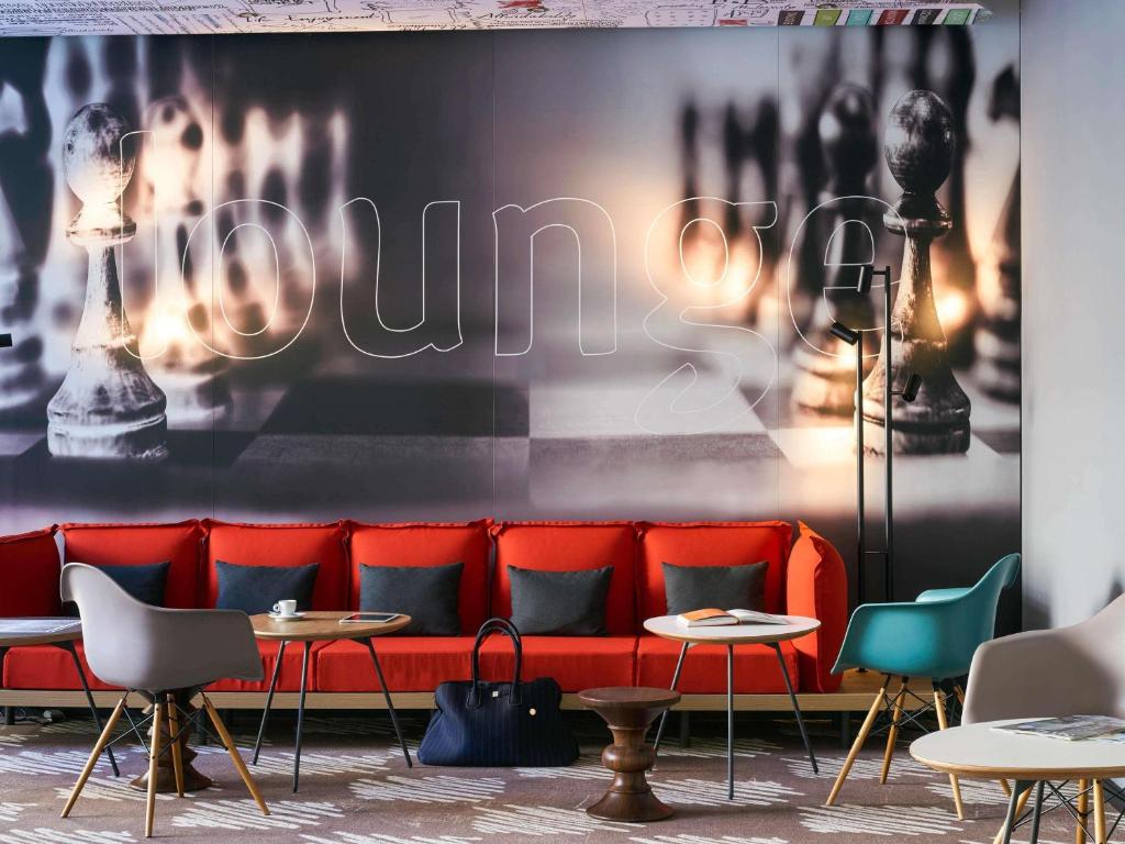 a red couch in a room with tables and chairs at ibis Jerusalem city Center - An AccorHotels Brand in Jerusalem