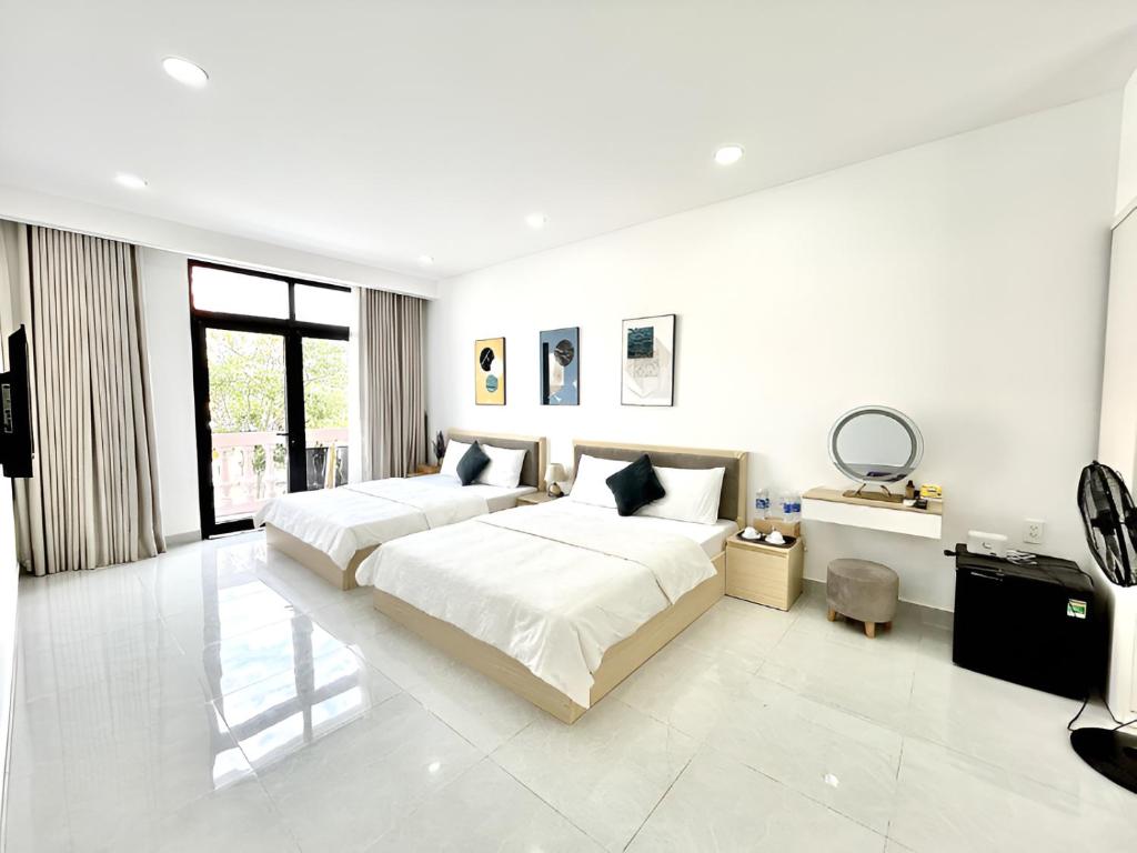 a white bedroom with two beds and a desk at Coconut Hotel in Phú Quốc