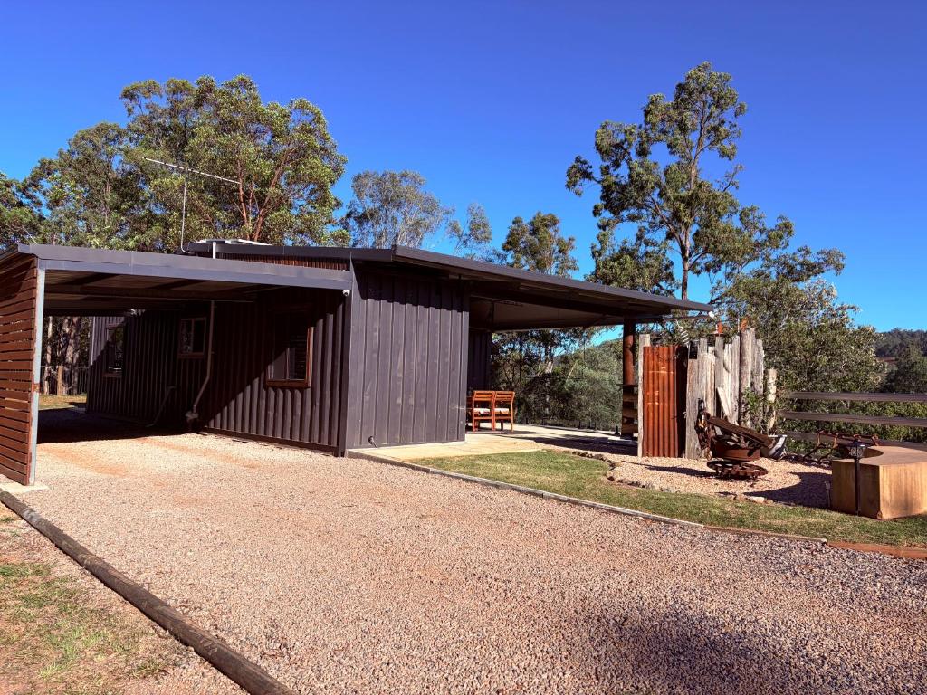 a black building on a gravel road next to a fence at Hayden's Place in Wamuran