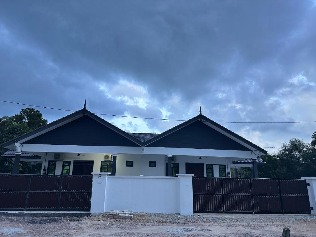 a house with a black roof and a white fence at Homestay Anaza in Kampong Balai Maras