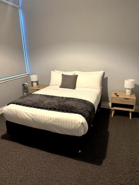 a bedroom with a bed with two nightstands and two lamps at Royal Hotel Tumut in Tumut