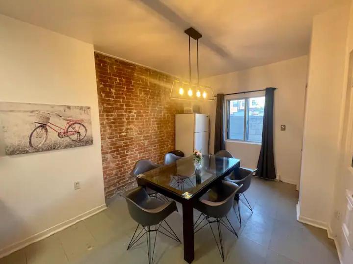 a dining room with a table and chairs and a brick wall at Full Kitchen METRO DE LEGLISE Room B in Montreal
