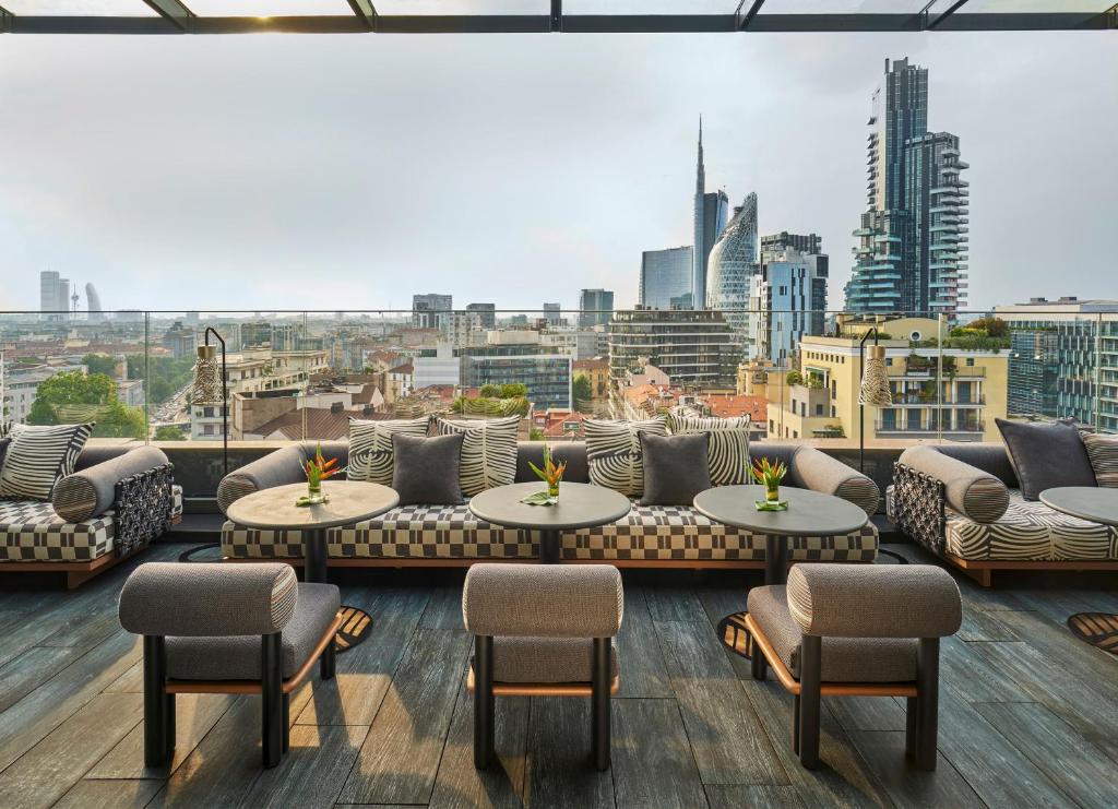 a rooftop patio with couches and tables and a view of a city at ME by Meliá Milan Il Duca in Milan