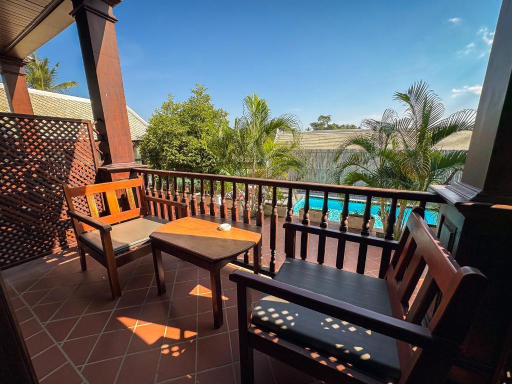 a balcony with two chairs and a table and a pool at NamKhan Riverside in Luang Prabang