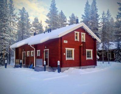 a red house with snow on top of it at Aabro, Levi in Kittilä