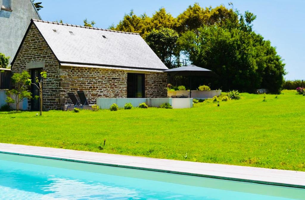a house and a yard with a swimming pool at La petite maison de Celestine in Plonéour-Lanvern