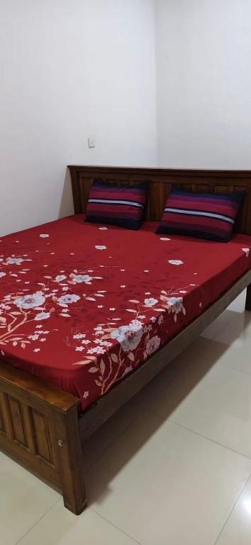 a bed with a red comforter and pillows on it at Elite moon hotel in Kallady