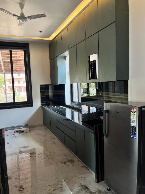 a kitchen with green cabinets and a stainless steel refrigerator at The Benjamins Pool Villa in Jodhpur