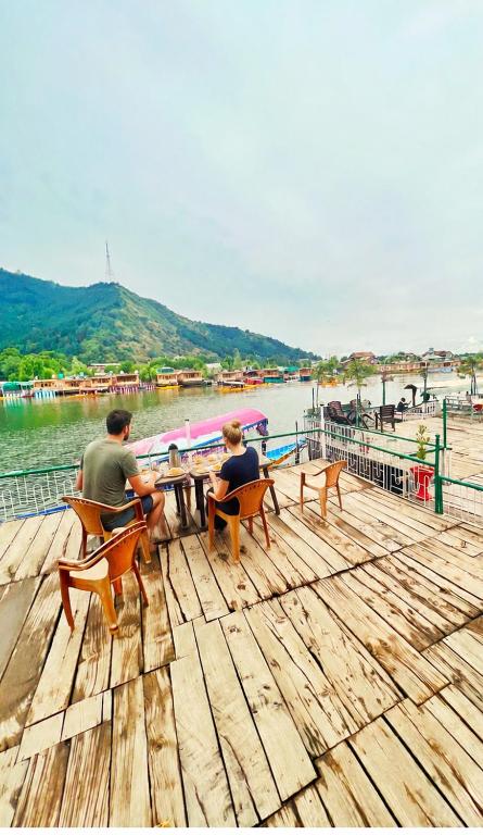 a couple of people sitting at a table on a dock at Budget Cottage By Aristotle in Srinagar