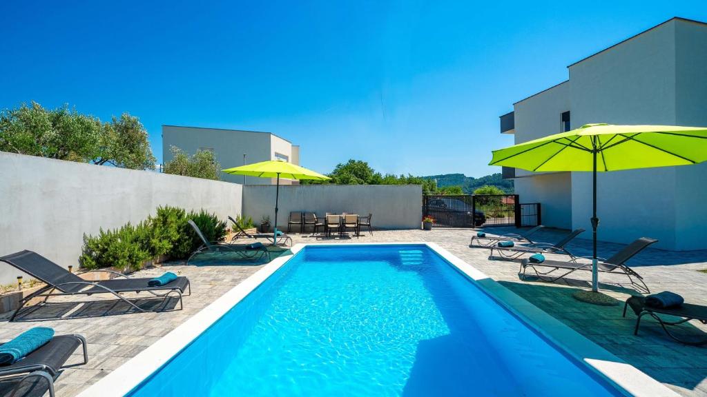 a swimming pool with chairs and umbrellas next to a building at Villa Rab Paradise pool by Villas Guide in Lopar