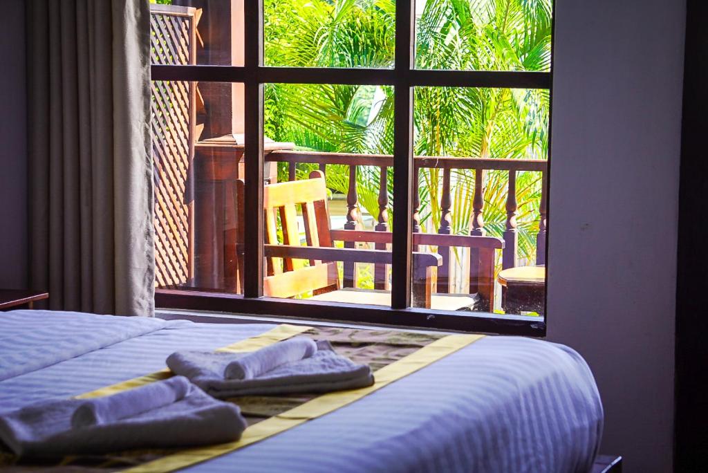 a bedroom with a bed and a window with towels at Namkhan Riverside Hotel in Luang Prabang