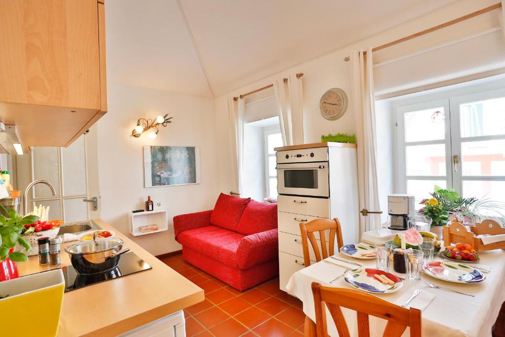 a kitchen with a table and a red couch in a kitchen at Apartments im Garten - Haus Anna in Graz