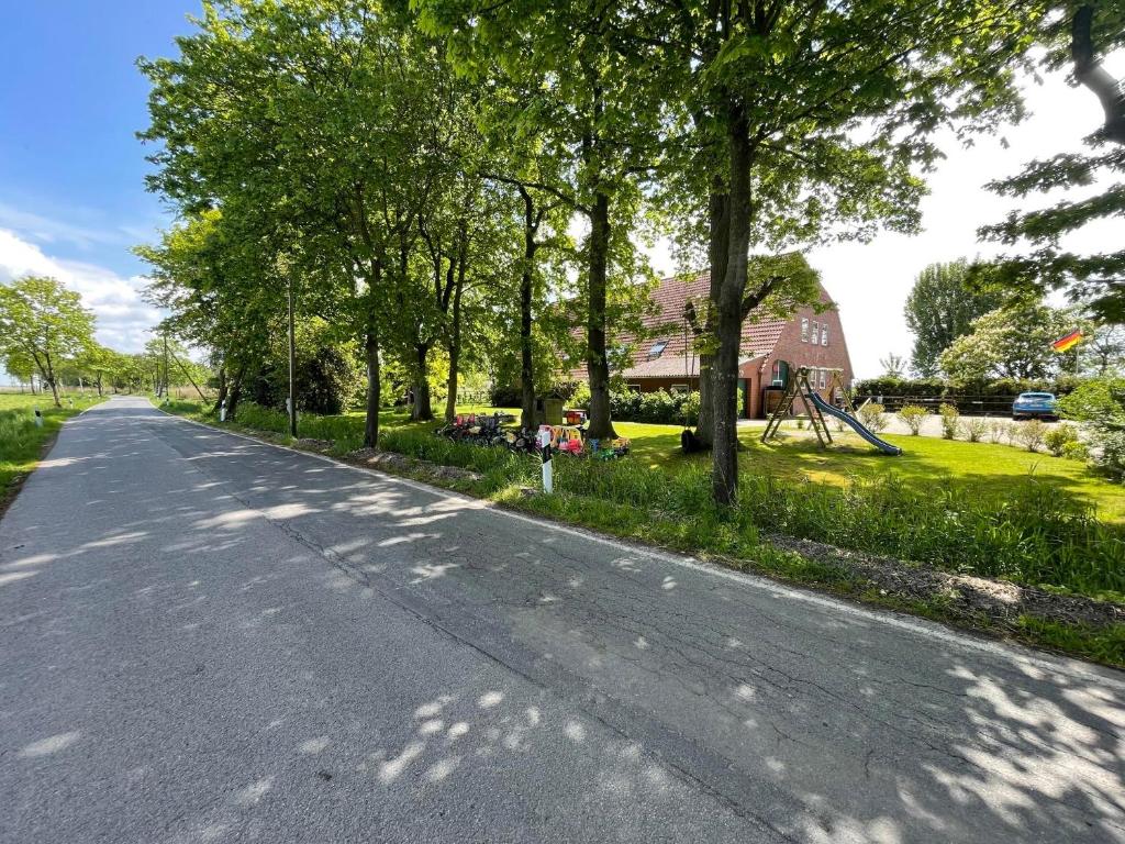 an empty road in front of a house with trees at Wattenmeer-Ferien in Süllwarden