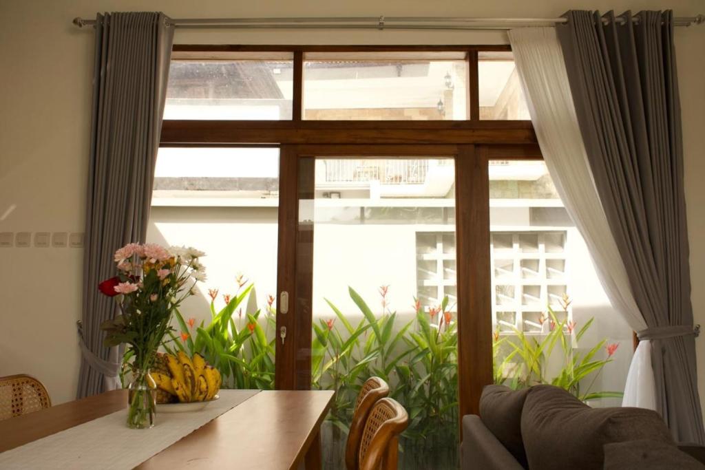 a table with a vase of flowers and a window at Selena Home Tropical Villa Jimbaran in Jimbaran