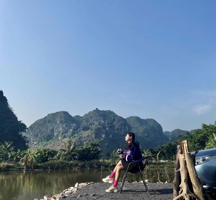 a woman sitting in a chair next to a river at Tràng An Gold in Xuân Sơn