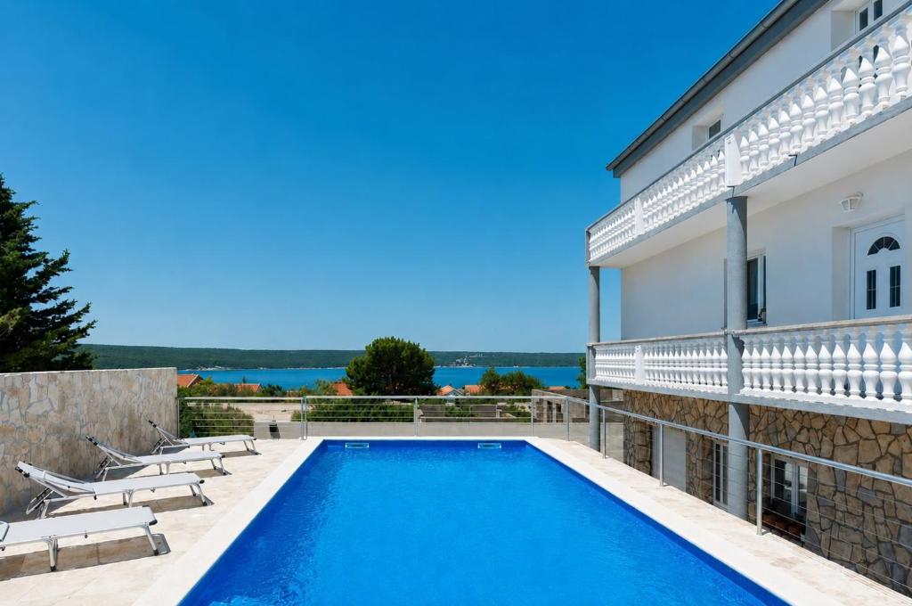 a swimming pool with lounge chairs next to a building at Apartments Ana in Gornji Karin